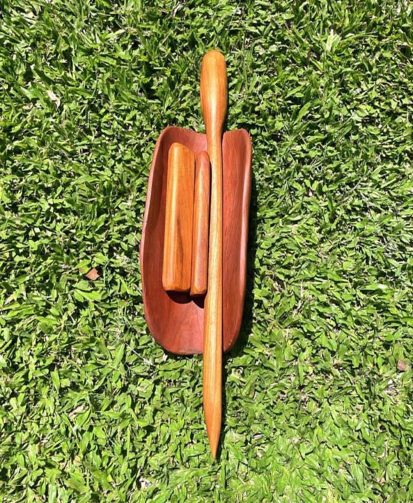 A wooden stick is sitting on top of a tray on the grass.