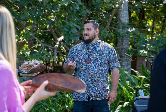 A man and a woman are standing next to each other holding wooden plates.