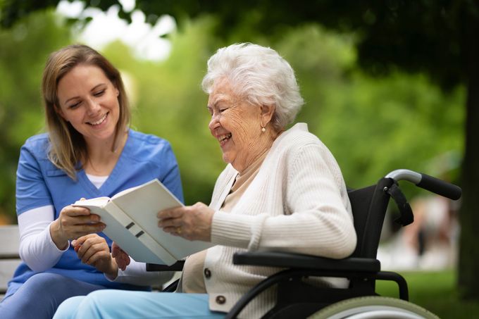 A Nurse Is Reading A Book To An Elderly Woman - DeSoto, TX - Amazing Hearts Homecare & Staffing A Nurse Is Reading A Book To An Elderly Woman - DeSoto, TX - Amazing Hearts Homecare & Staffing