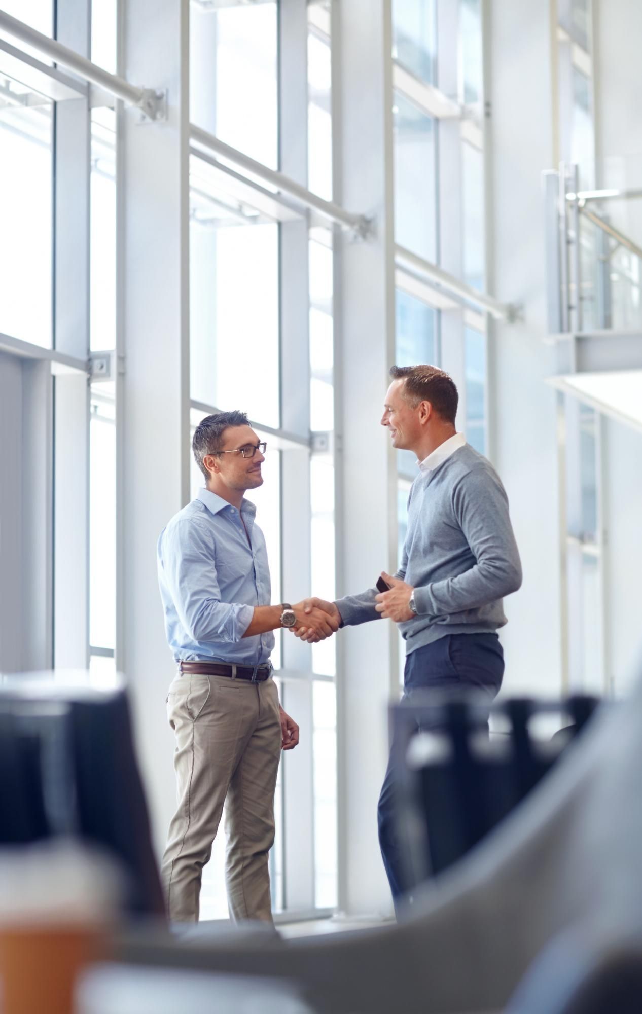 Two professionals shaking hands in a bright modern office atrium