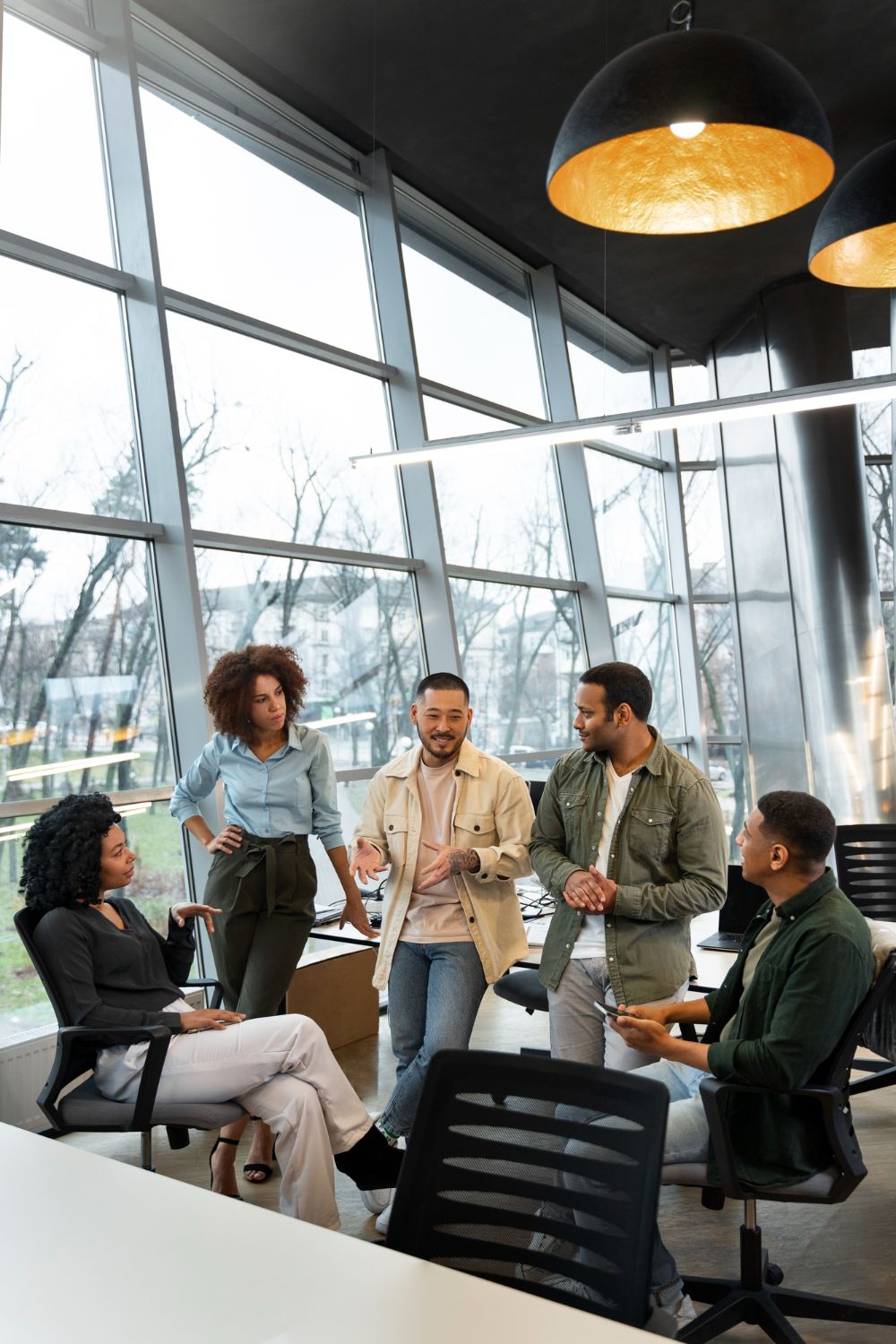 Five colleagues in a bright office lounge discussing ideas around a table