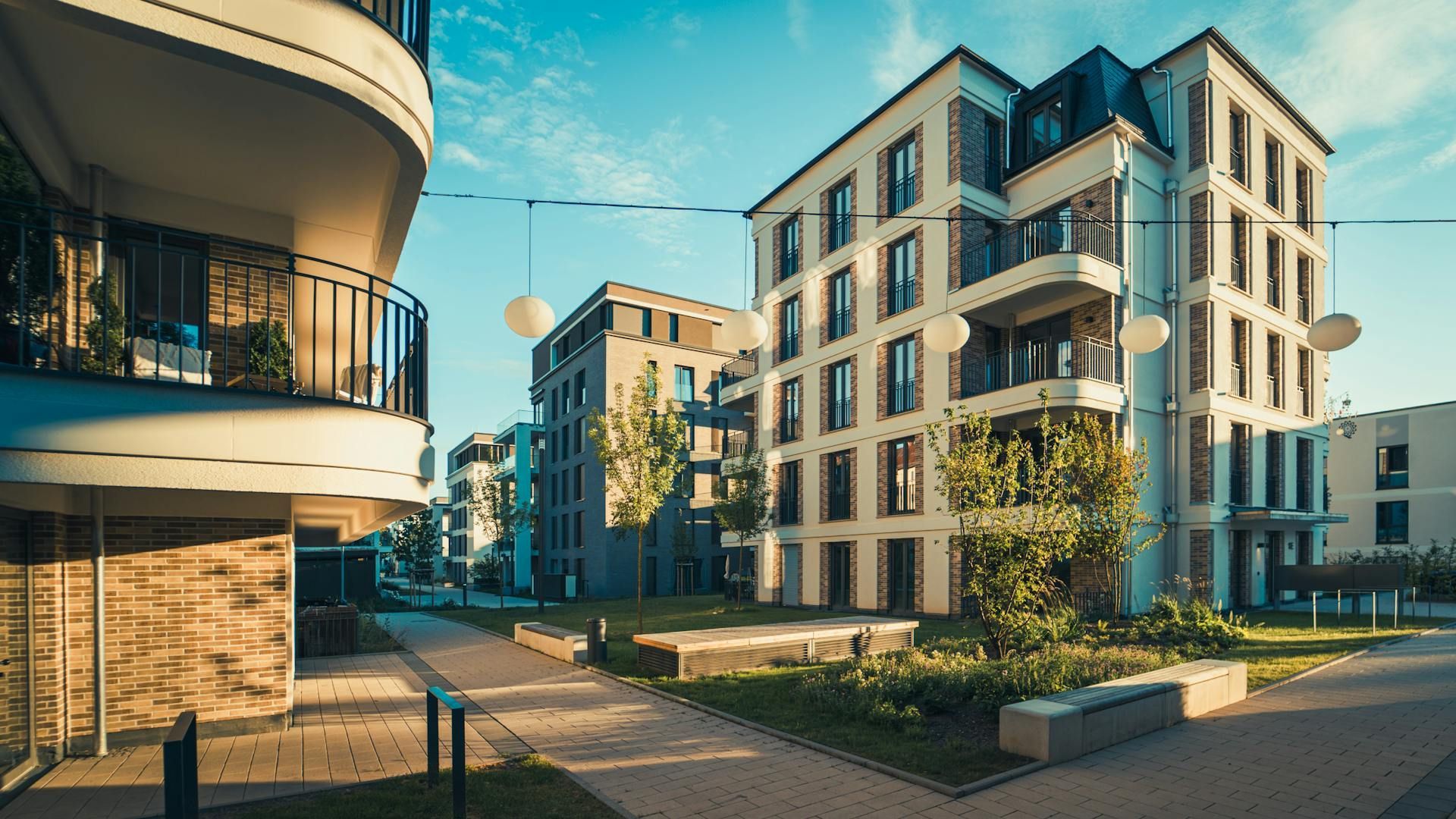 Modern apartment complex with balconies and landscaped courtyard in warm afternoon light