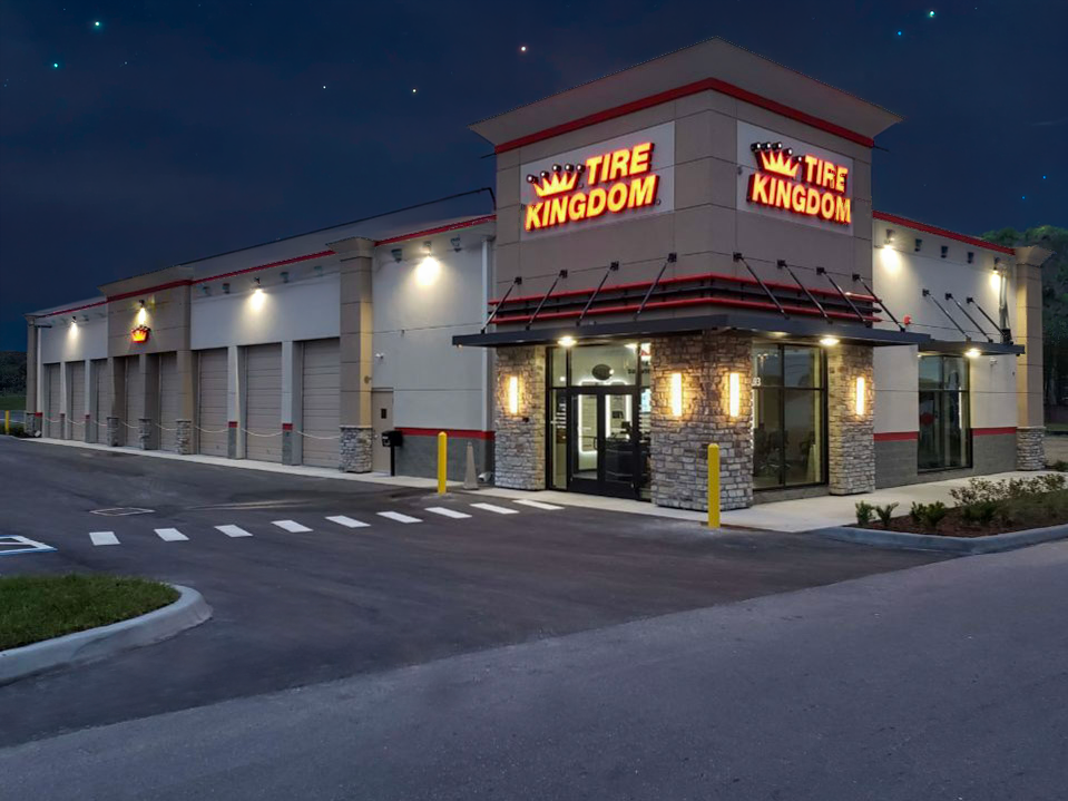 Tire Kingdom auto service store at dusk, with lit storefront and garage bays on a corner lot
