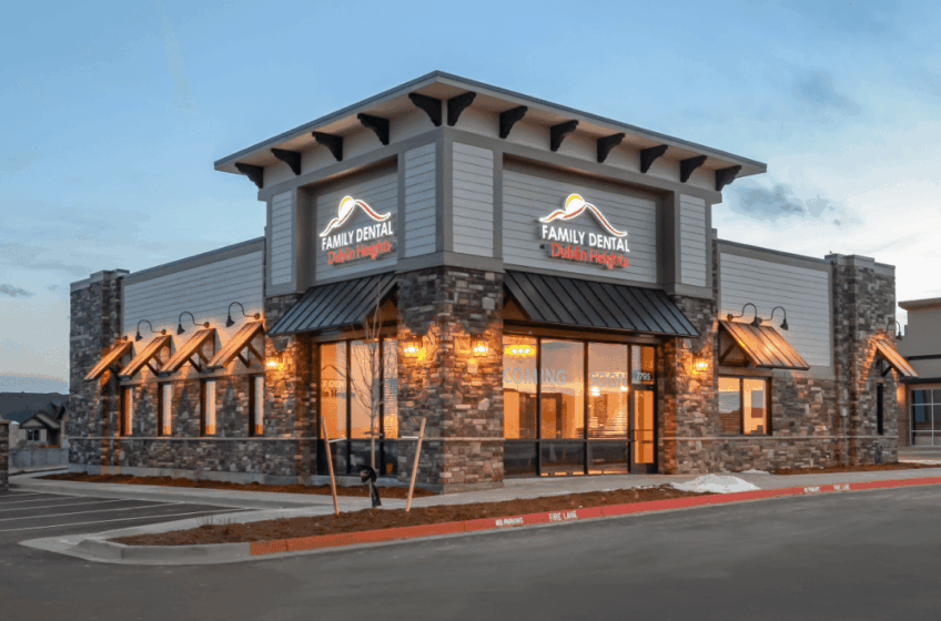 Modern restaurant exterior at dusk with stone walls, warm lights, and a corner entrance