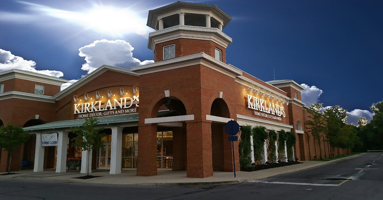 Brick shopping center with arched windows and tower under a cloudy sky at dusk