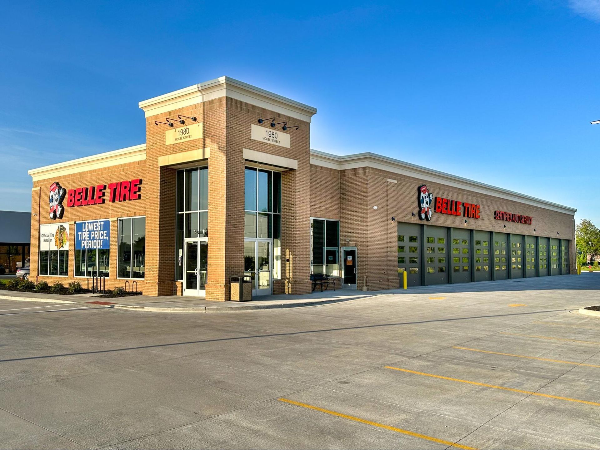 Blue Tire auto service building with garage bays and a tan brick facade under a clear blue sky