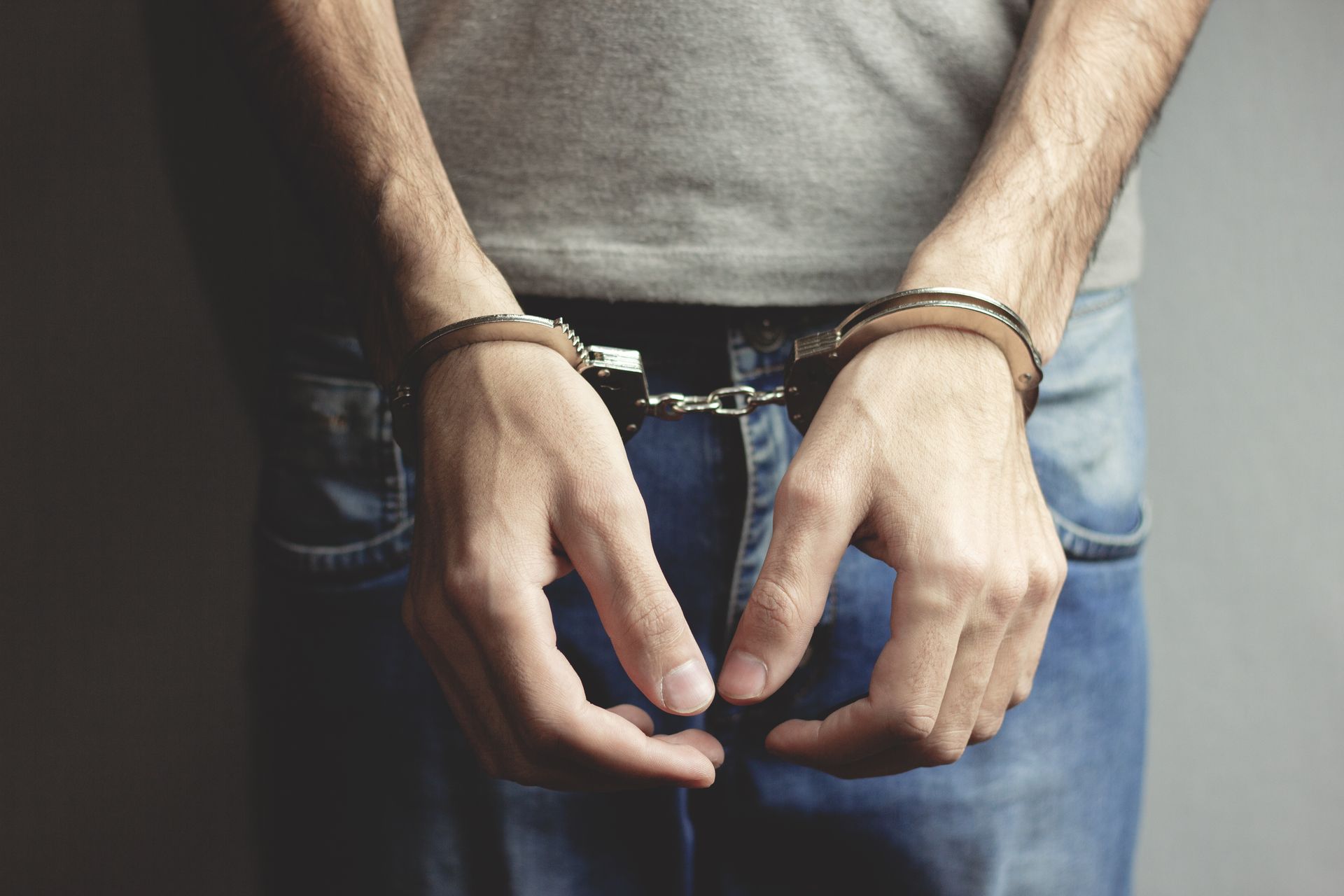 Young man hand handcuffs on dark background.