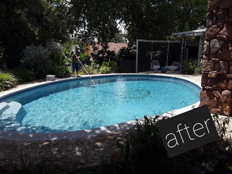 A large swimming pool with a fence around it and trees in the background.