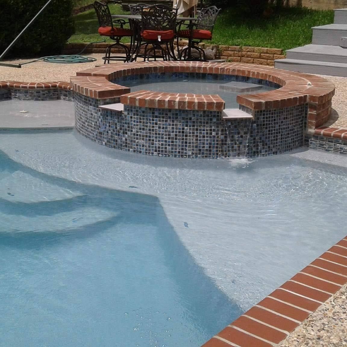 There is a large swimming pool in the backyard of a house.
