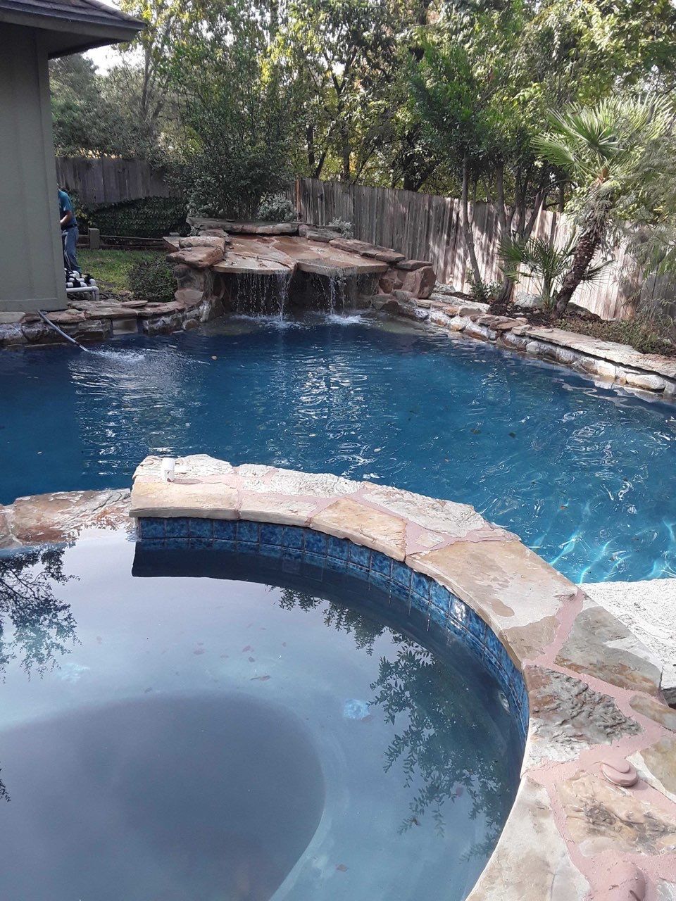 A large swimming pool with a waterfall in the backyard