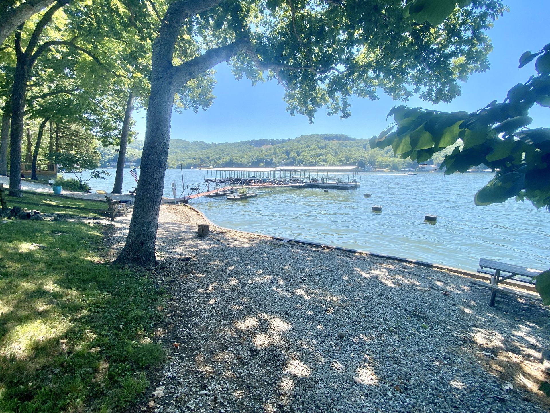 A view of a lake from a park with trees and a bench.