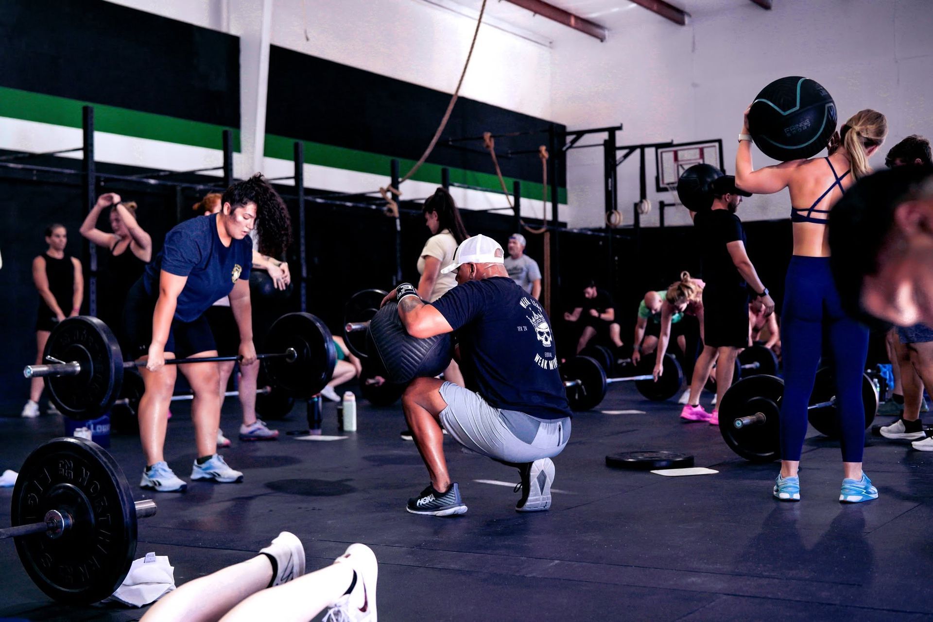 People exercising in a CrossFit gym in Baytown, TX, with one person lifting a kettlebell in the foreground