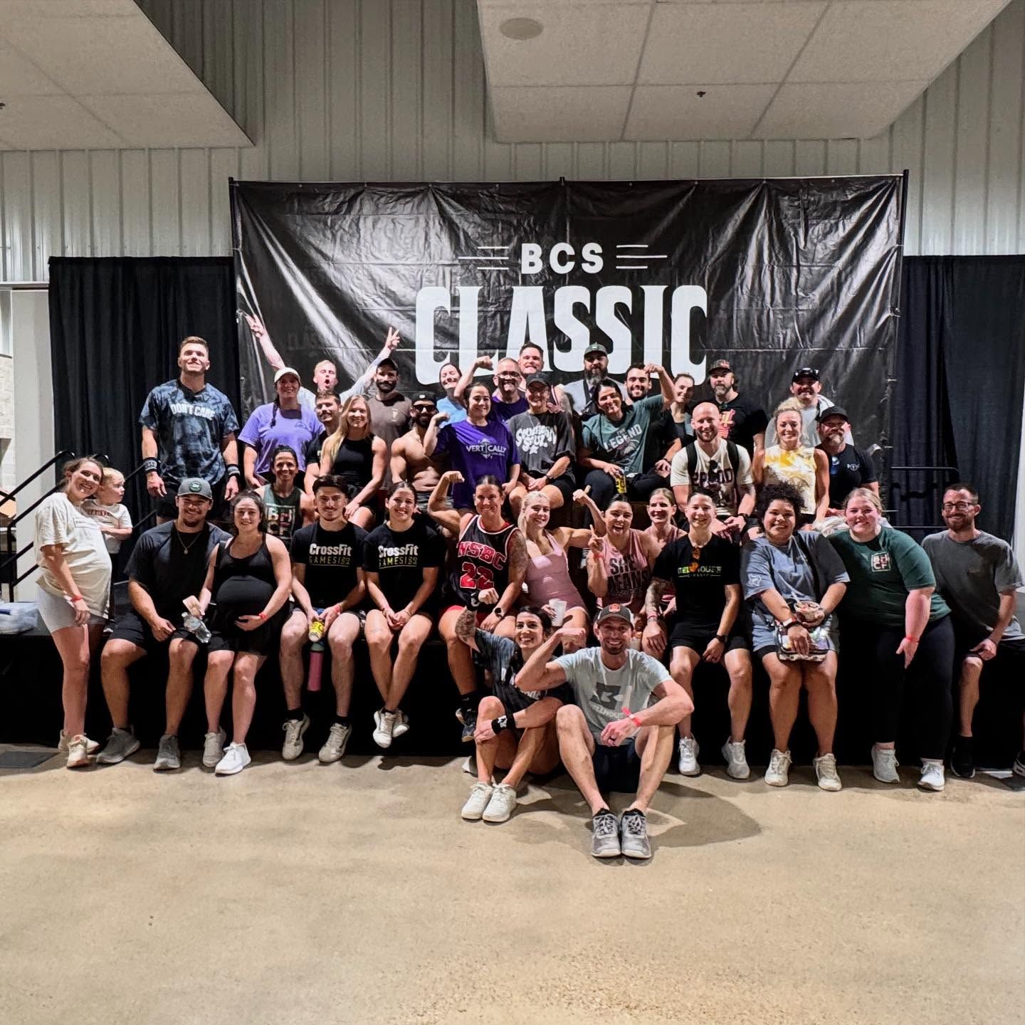 Large group posing indoors in front of a black “BCS Classic” banner