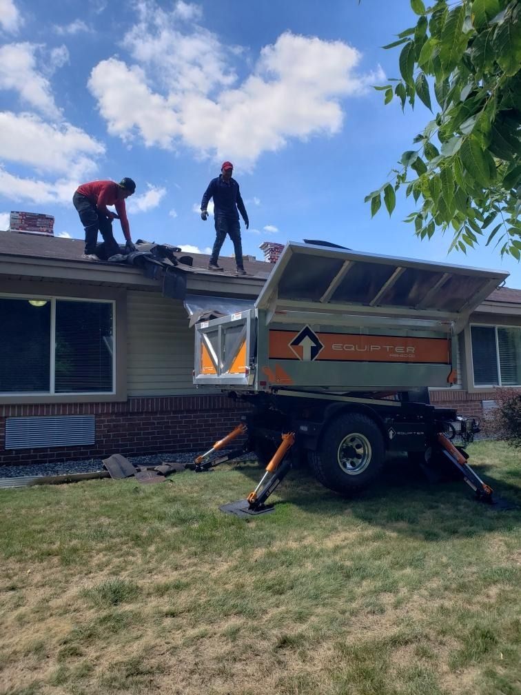 Two workers on a truck-bed lift repairing a roof under a blue sky