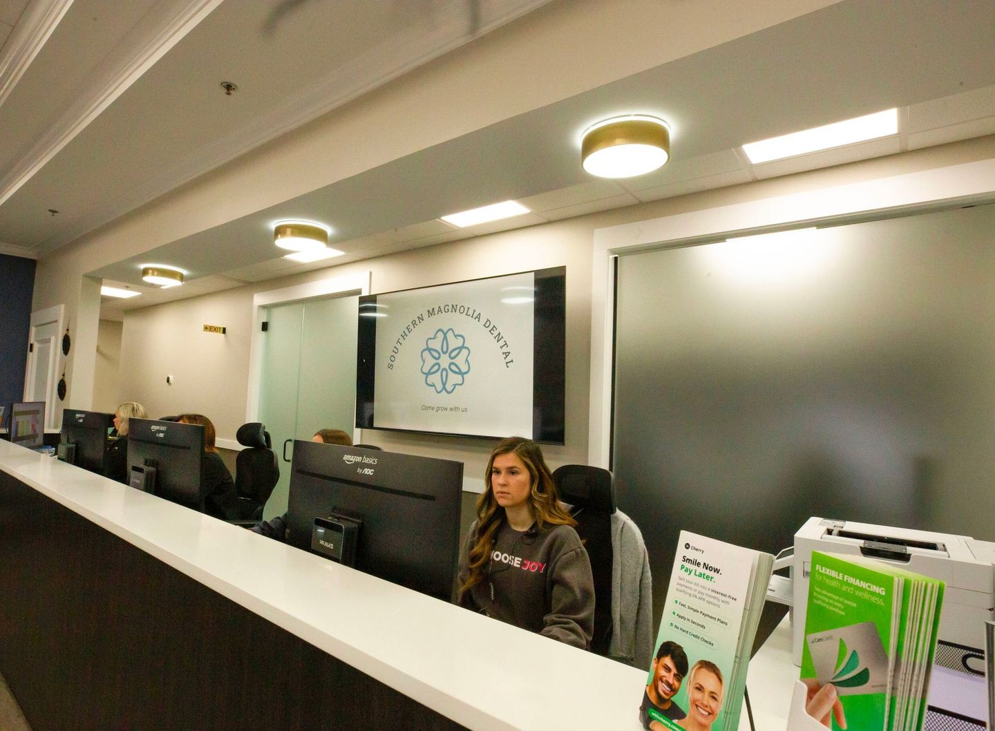 Office reception desk with two employees at computers and a frosted glass wall behind them