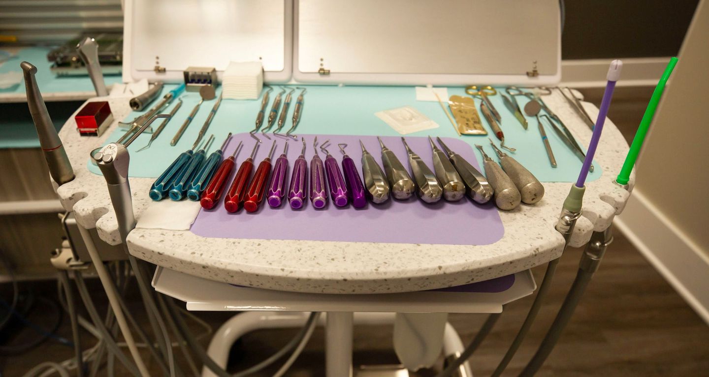Dental instruments arranged by color on a tray in a clinical treatment room