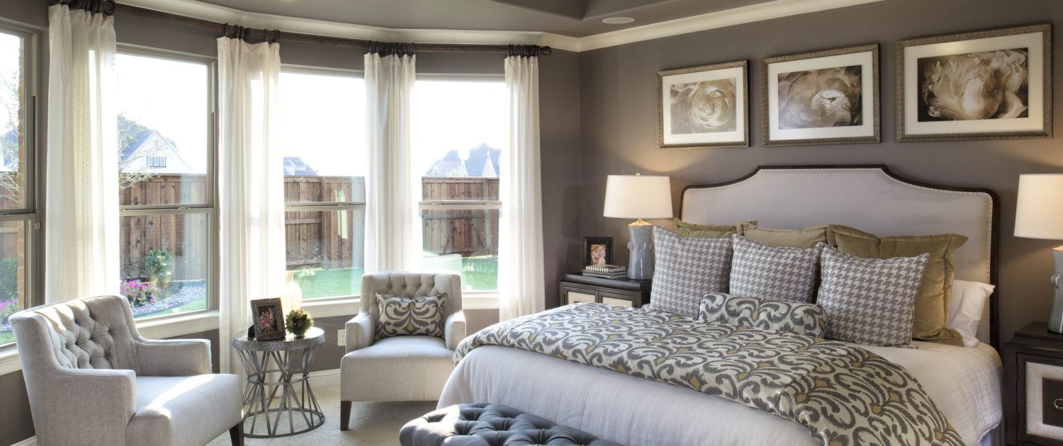 A bedroom with a large bed , chairs , lamps and a large window.