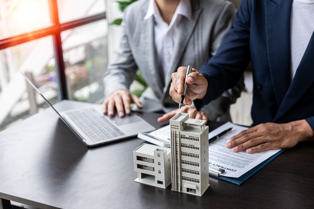 Businesspeople discussing a building model beside a laptop and notebook in a meeting room