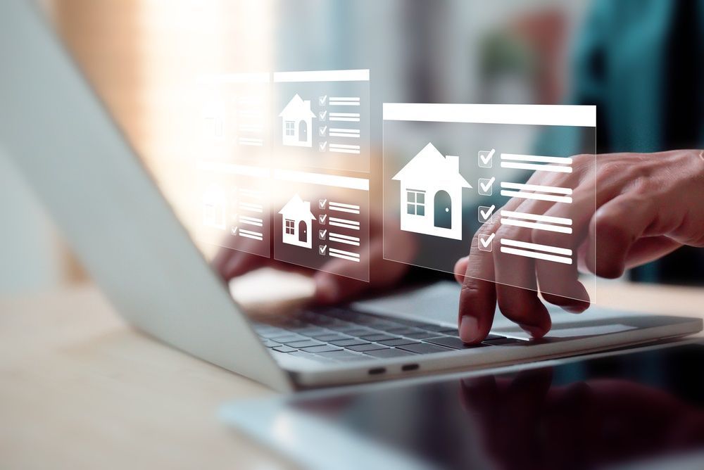 Hands typing on a laptop with floating house icons and checklists on the screen