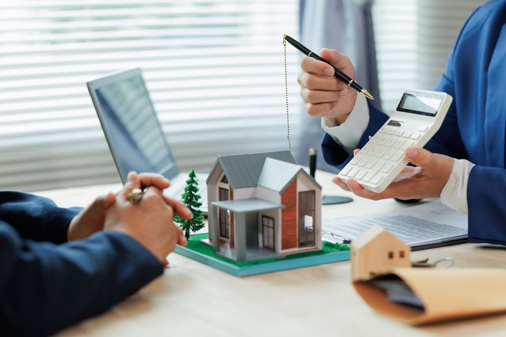 Agent showing a house model and paperwork during a real estate meeting