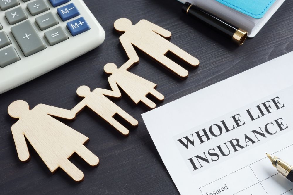 Whole life insurance form with wooden family figures and calculator on a desk