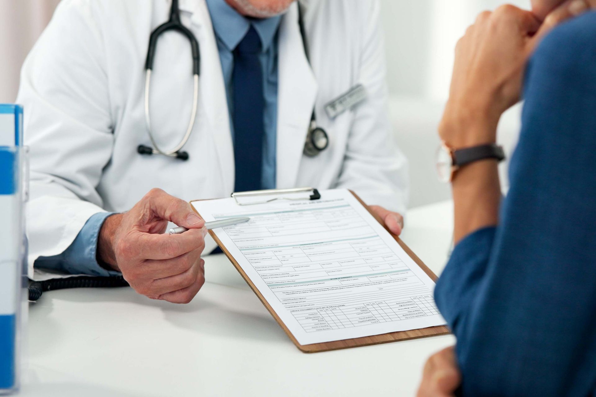 Doctor holding a clipboard and discussing paperwork with a patient in a clinic