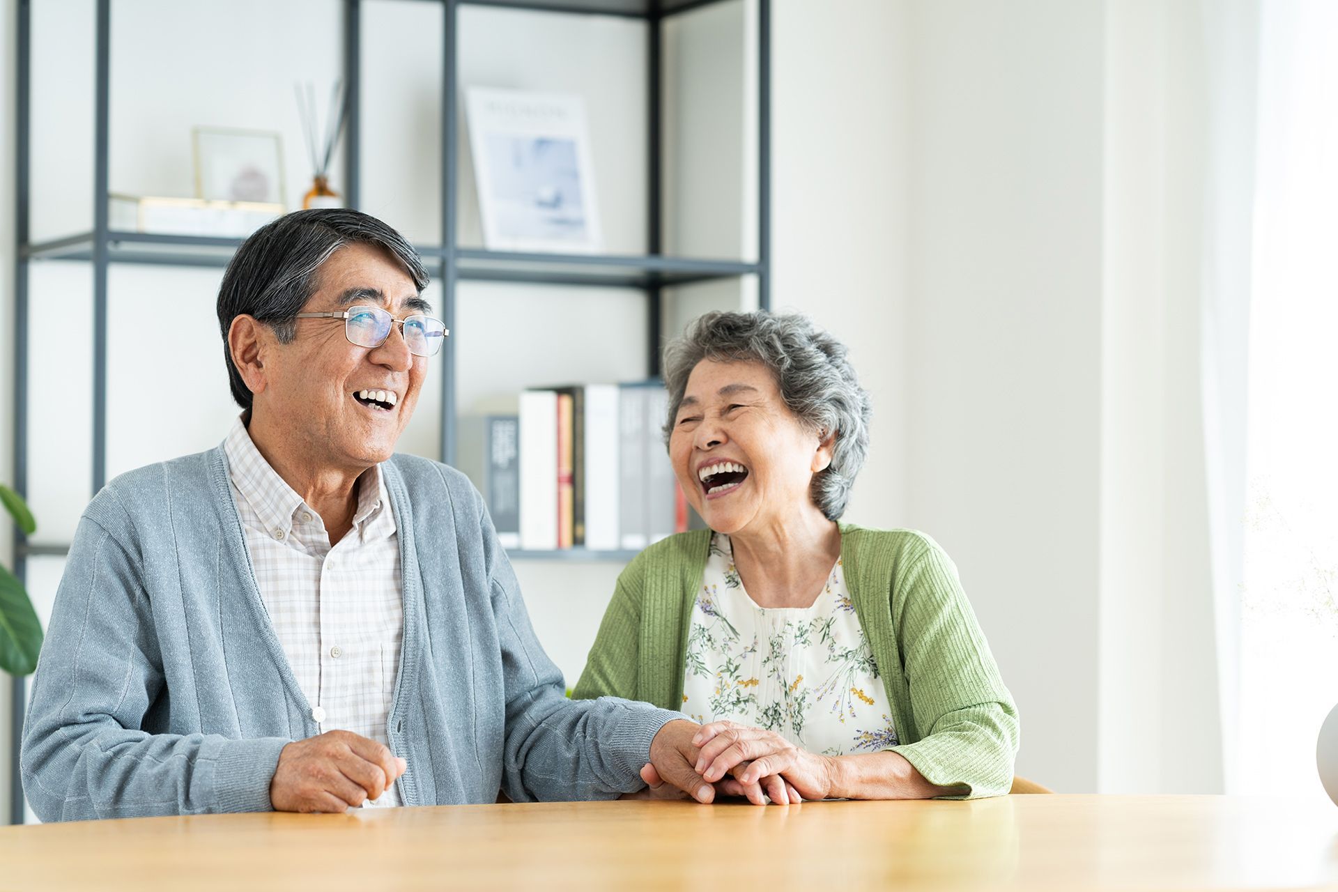 Two people laughing at a table in a bright, modern room