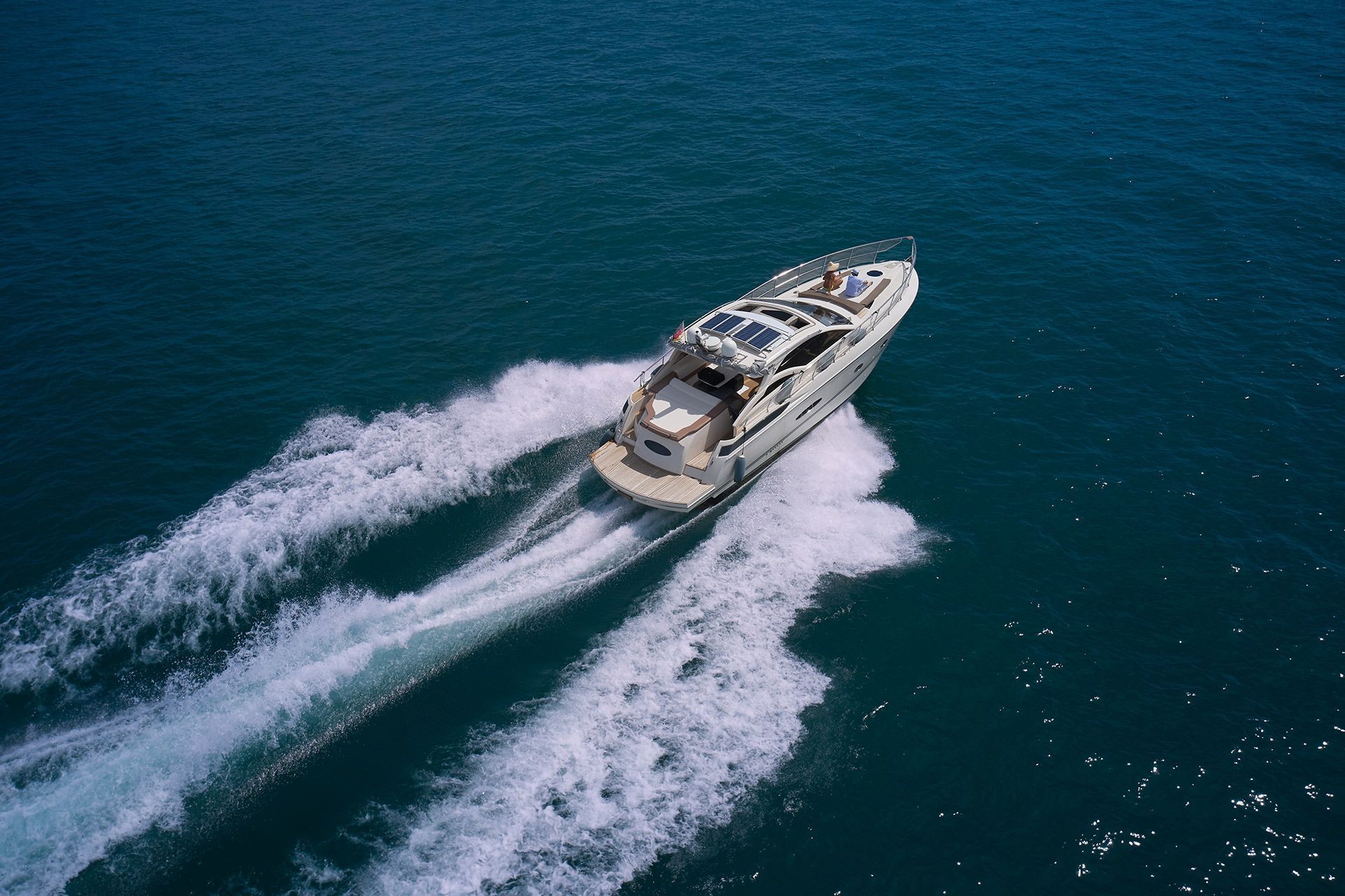 Motor yacht speeding across blue water, leaving a white wake behind.