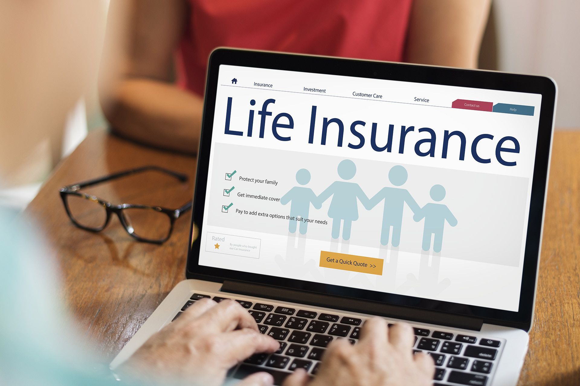 Laptop displaying life insurance website with family graphic and a pair of glasses nearby