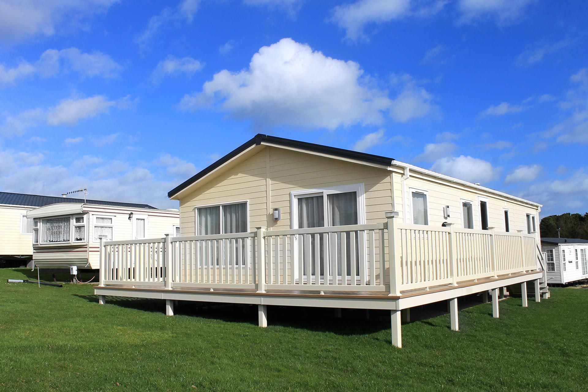 Modular home with white porch on green grass under a blue sky