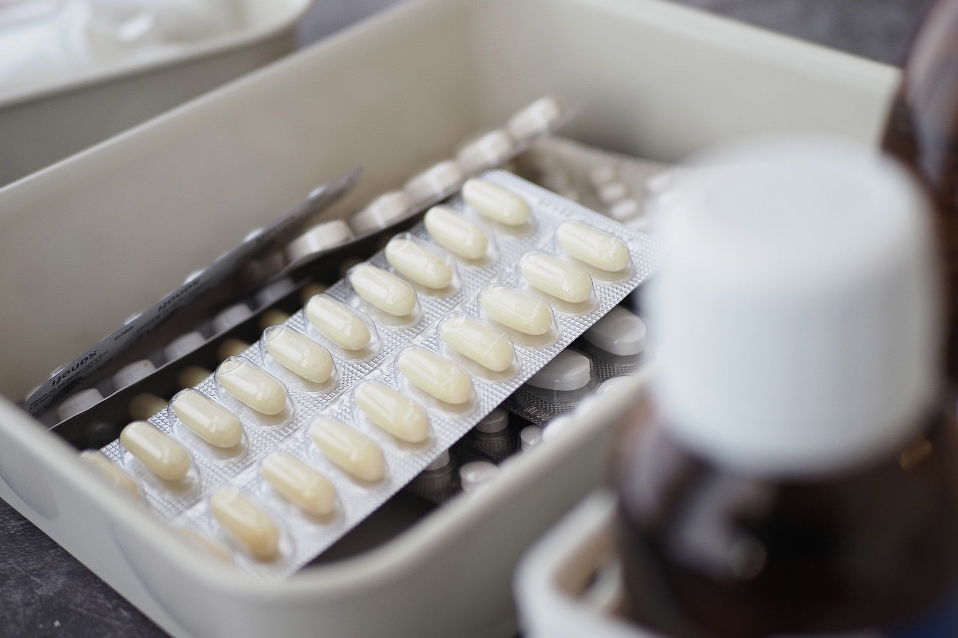 Tray of white dental aligners in a box, with a blurred bottle in the foreground