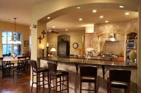 A kitchen with a bar and stools and a dining room in the background.