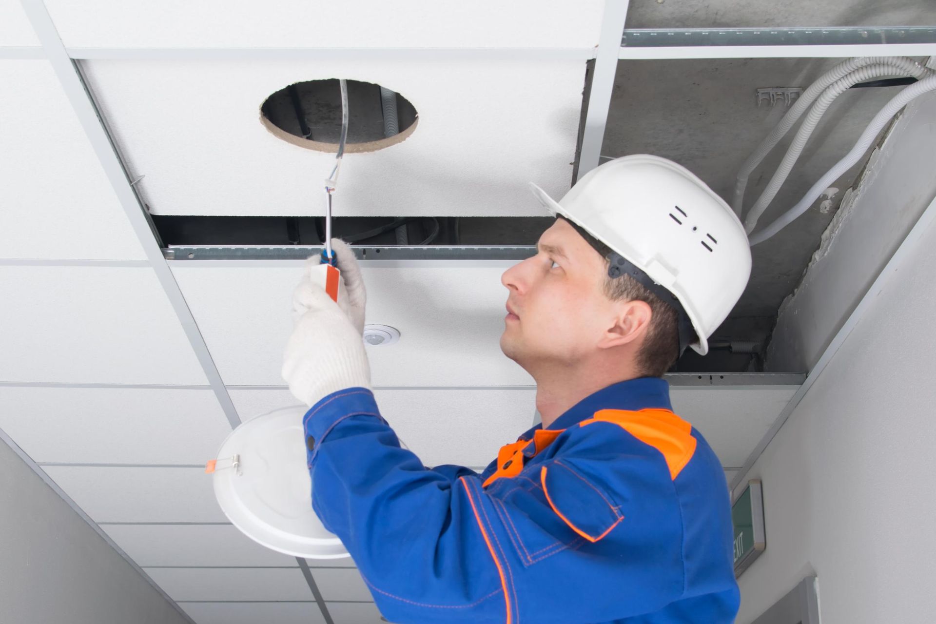 A man is working on a ceiling with a screwdriver.