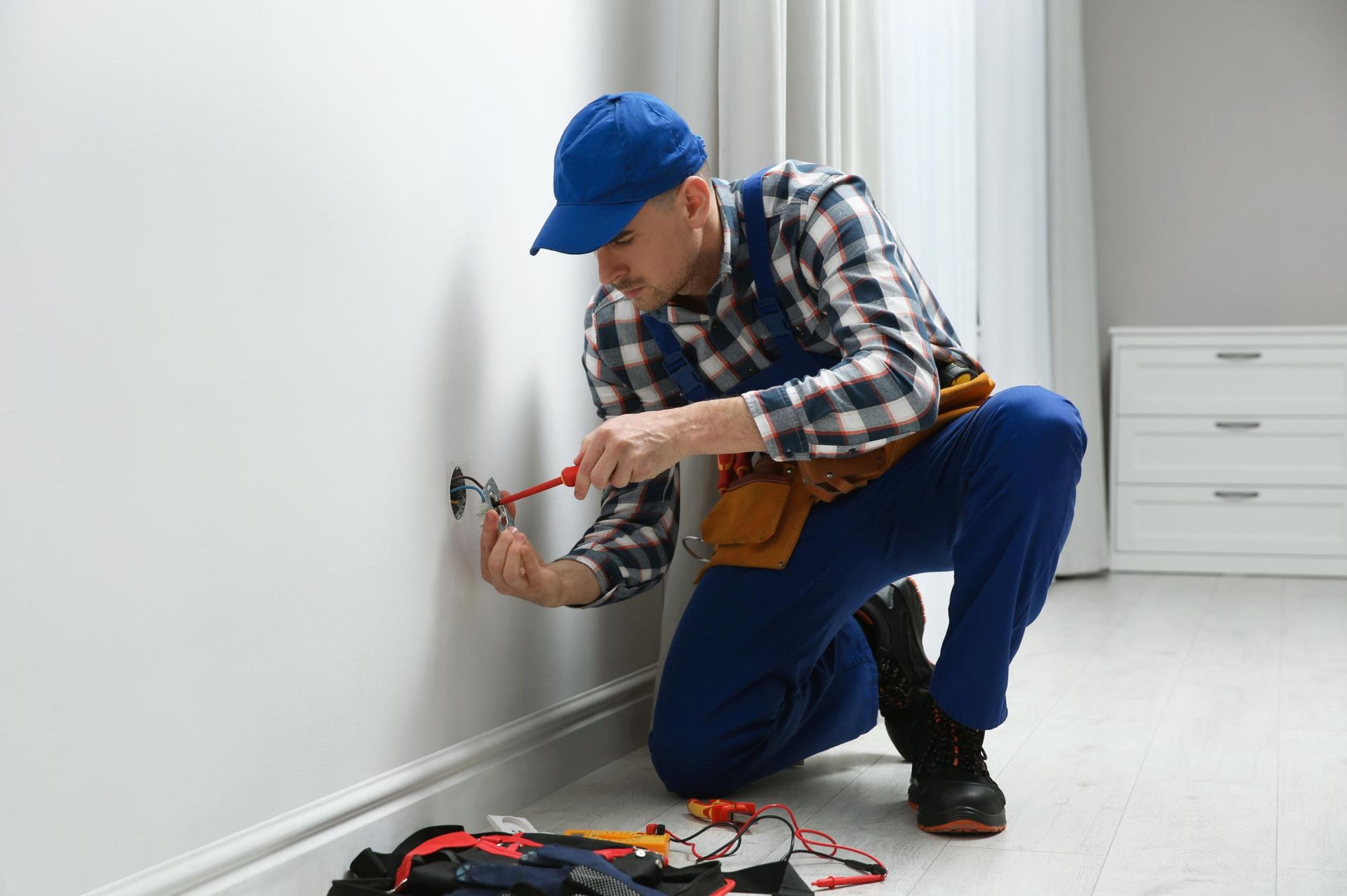 A man is working on a wall with a hammer and a screwdriver.