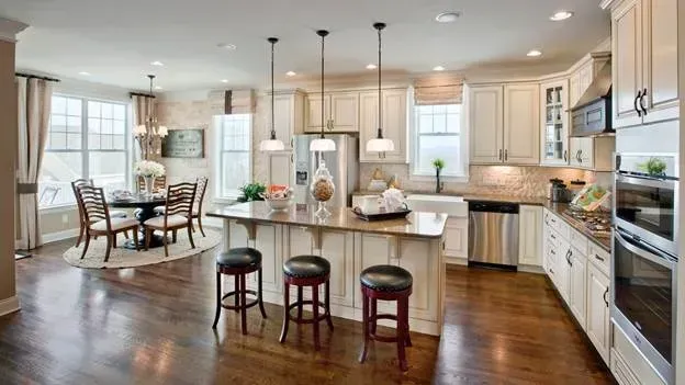 A kitchen with white cabinets and stainless steel appliances and a large island in the middle.