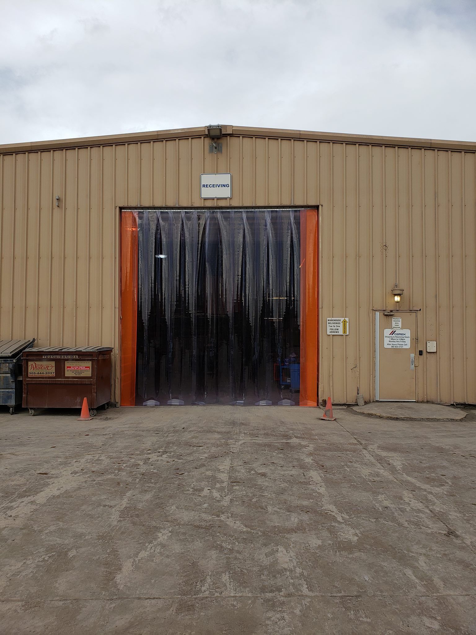 Building with loading dock covered by black plastic strips; brown and orange exterior.