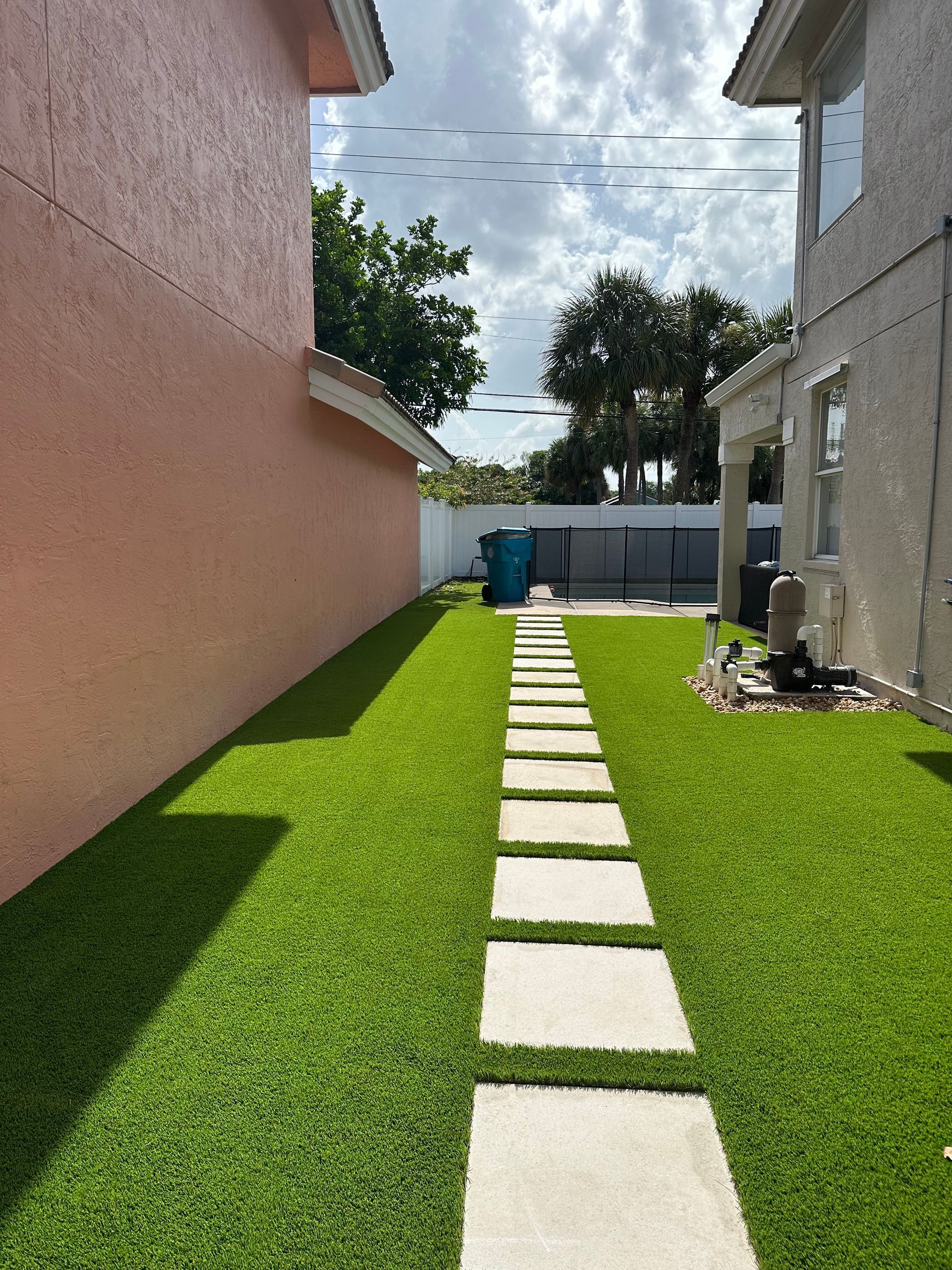 A walkway leading to a house with a lush green lawn.