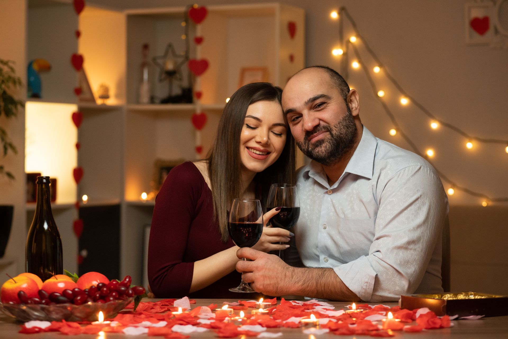 casal apaixonado em jantar a luz de velas segurando taças de vinho