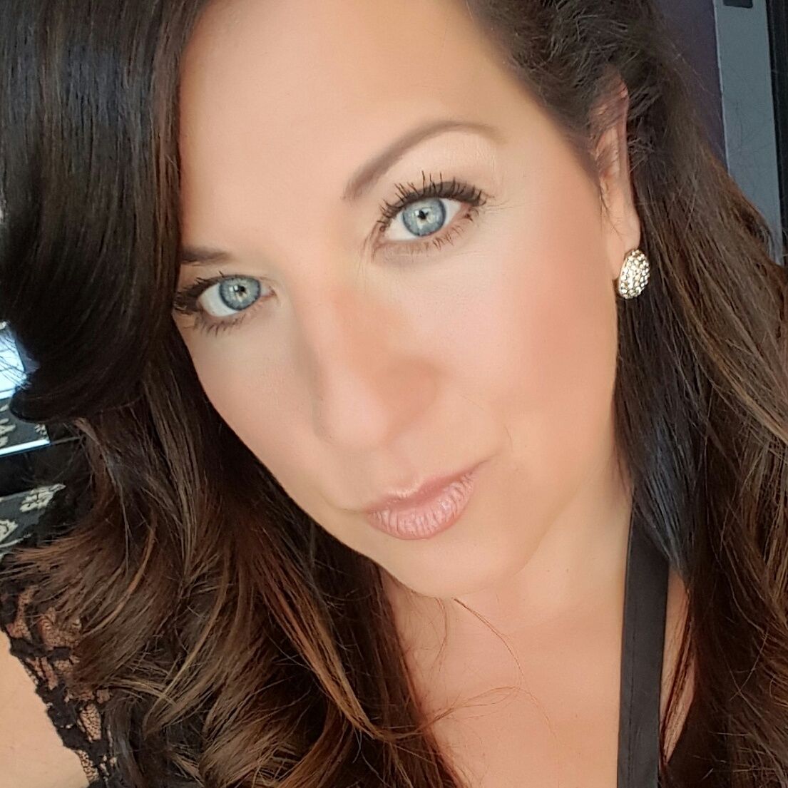 Woman with light skin, blue-green eyes, and brown hair. Soft lighting, looking towards the viewer.
