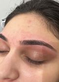 Close-up of a person's closed eye and eyebrow. The eyebrow is dark and well-defined; the skin is lightly flushed.
