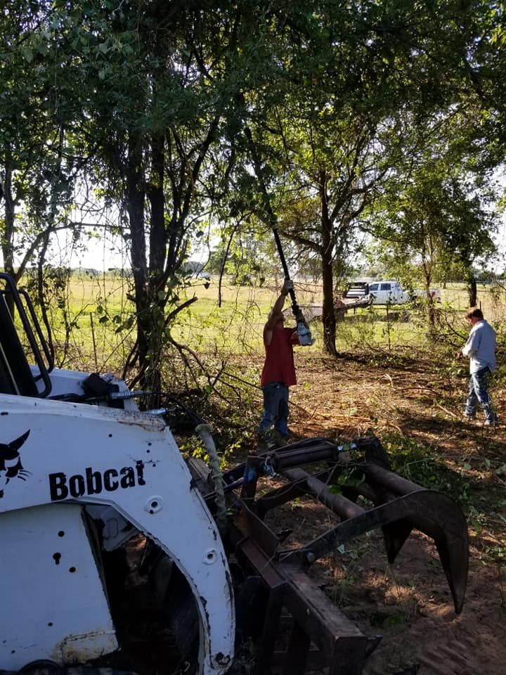 A man is standing next to a bobcat tractor in a field.