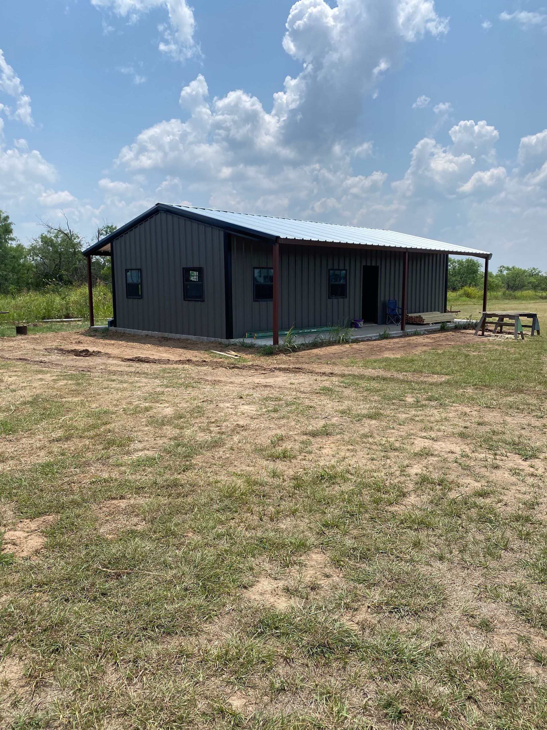 A metal building with a canopy over it is sitting on top of a dirt hill.
