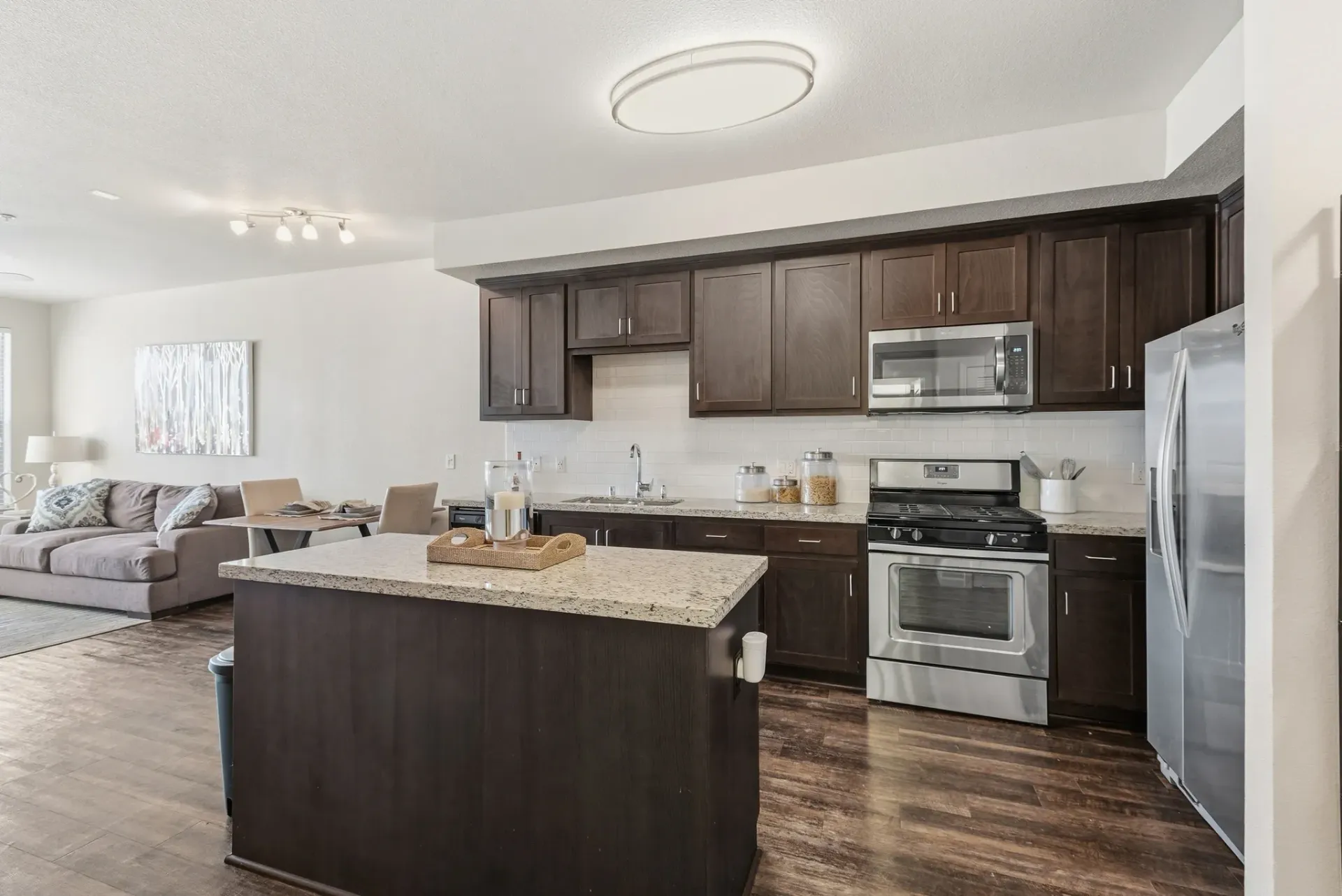 Modern kitchen with dark wood cabinets, stainless steel appliances, granite countertops, and an island.