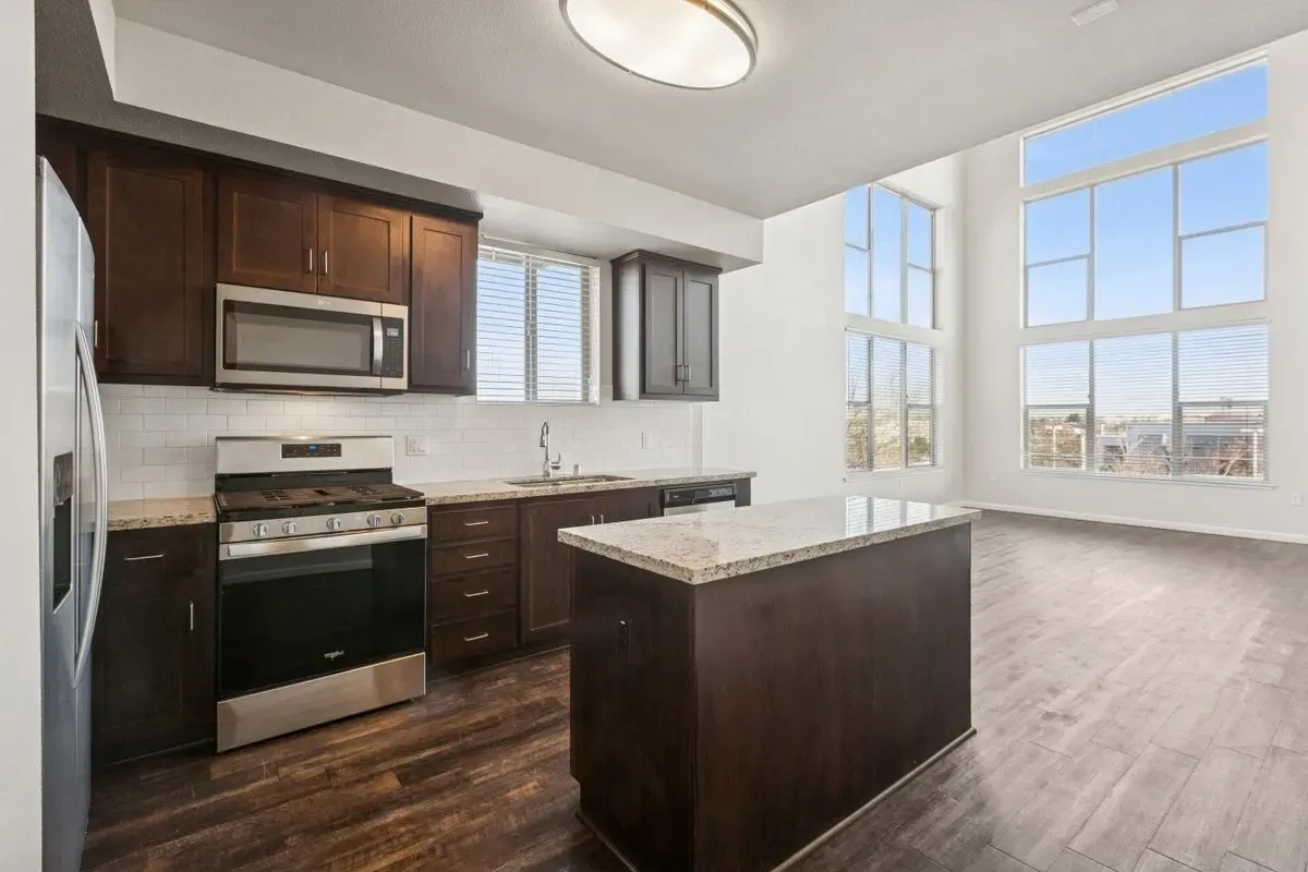 Modern kitchen with dark wood cabinets, granite countertops, and stainless steel appliances.