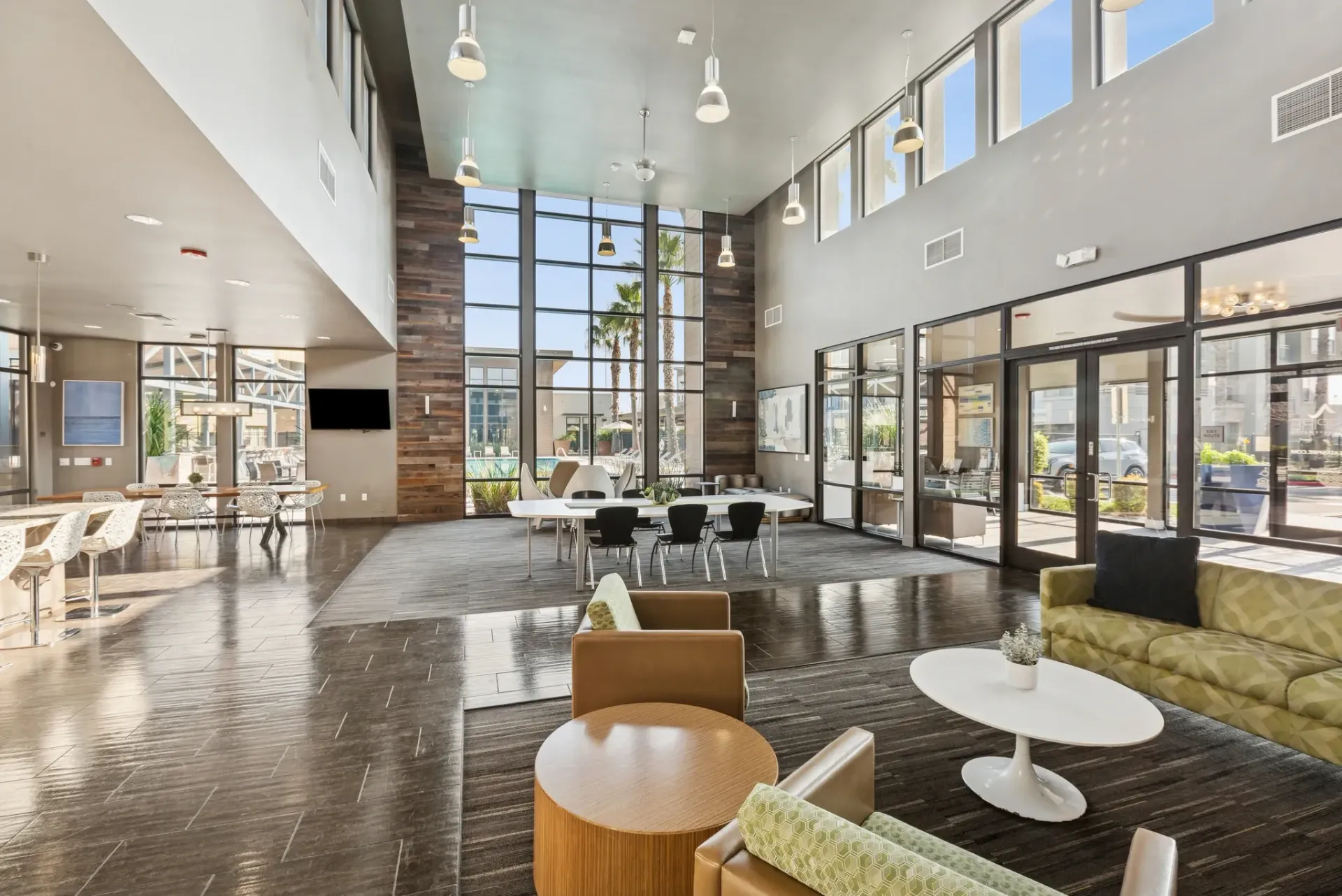 Spacious and modern lounge area with high ceilings, large windows overlooking a pool, and comfortable seating.