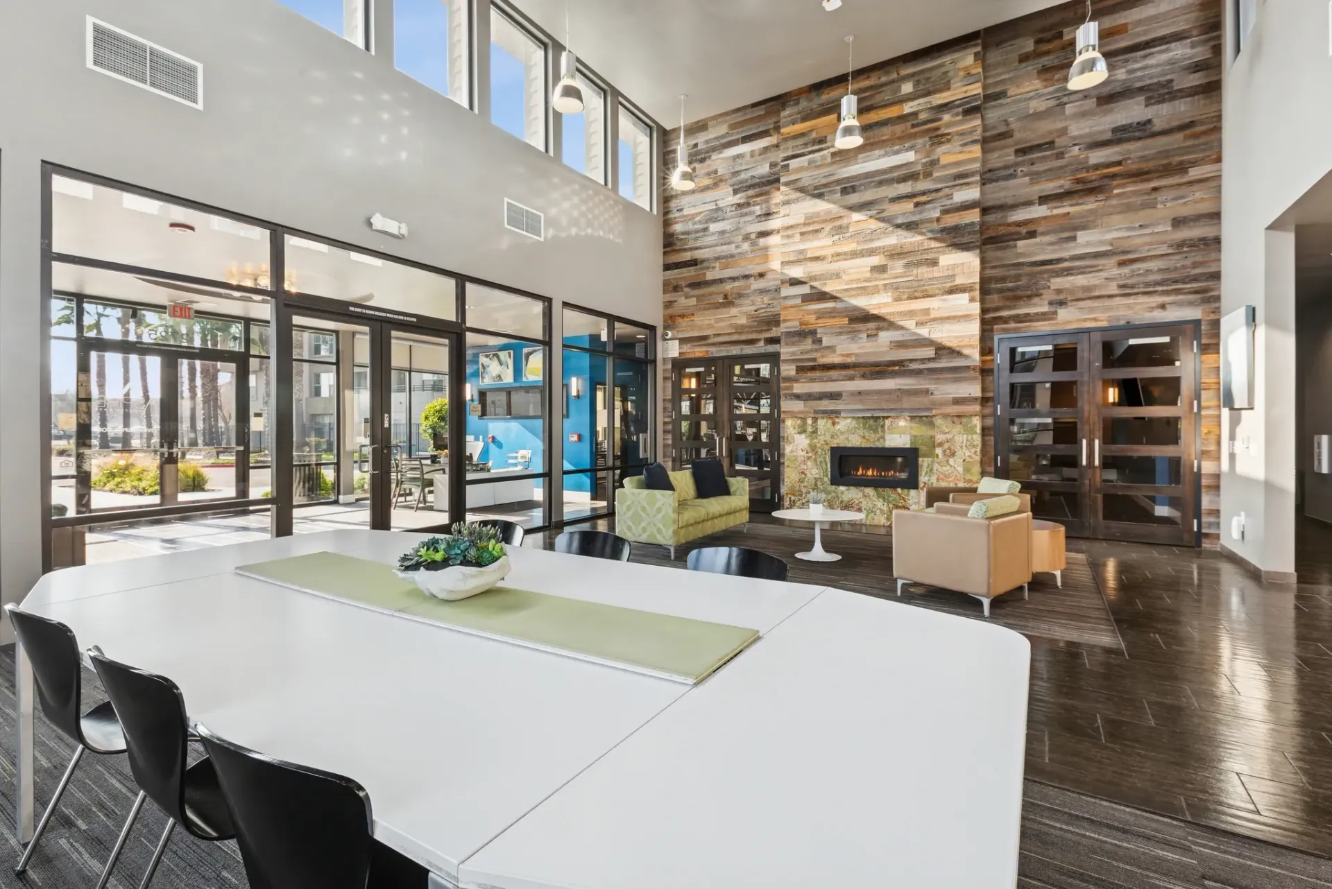 Modern common area with large table, fireplace, and seating.