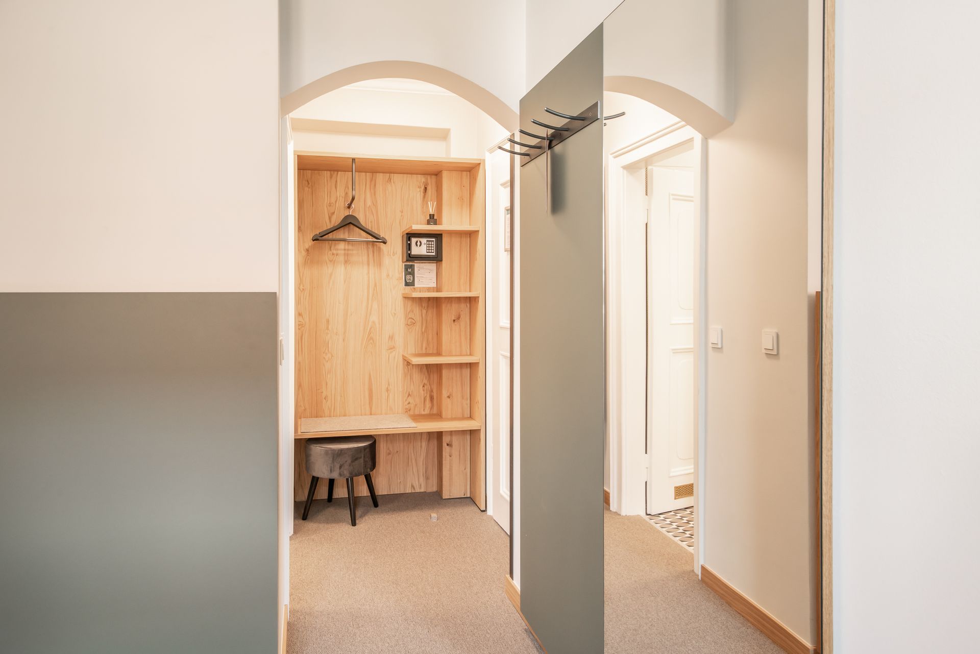 Hallway with wooden closet, mirror, and doorway leading to another room.
