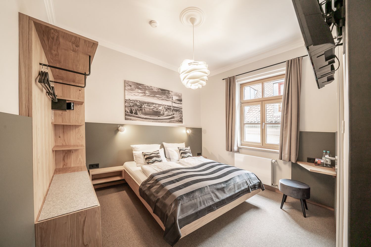Hotel bedroom with a bed, artwork, and wooden accents.