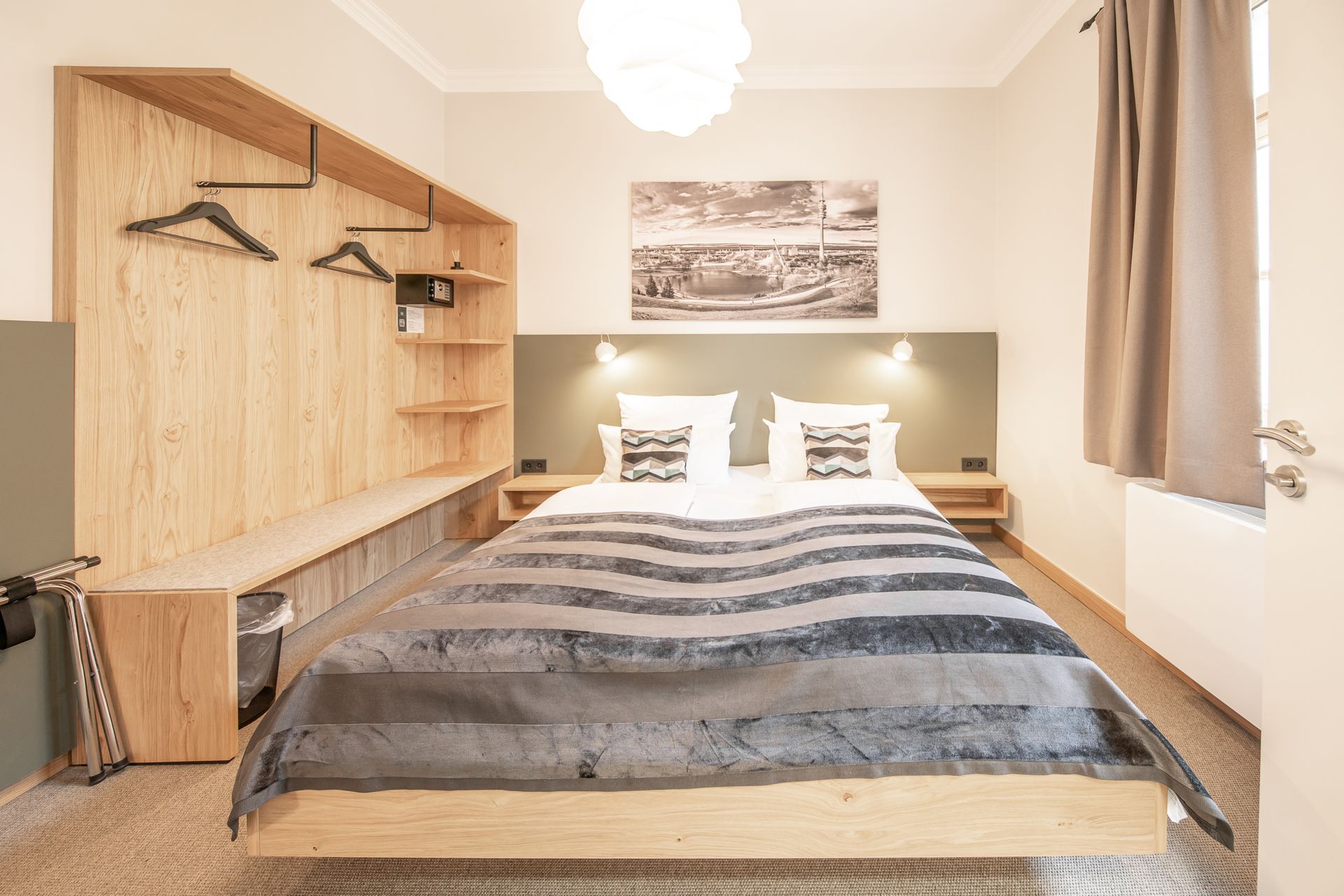 Bedroom with wooden bed frame and storage unit, neutral colors, and artwork.