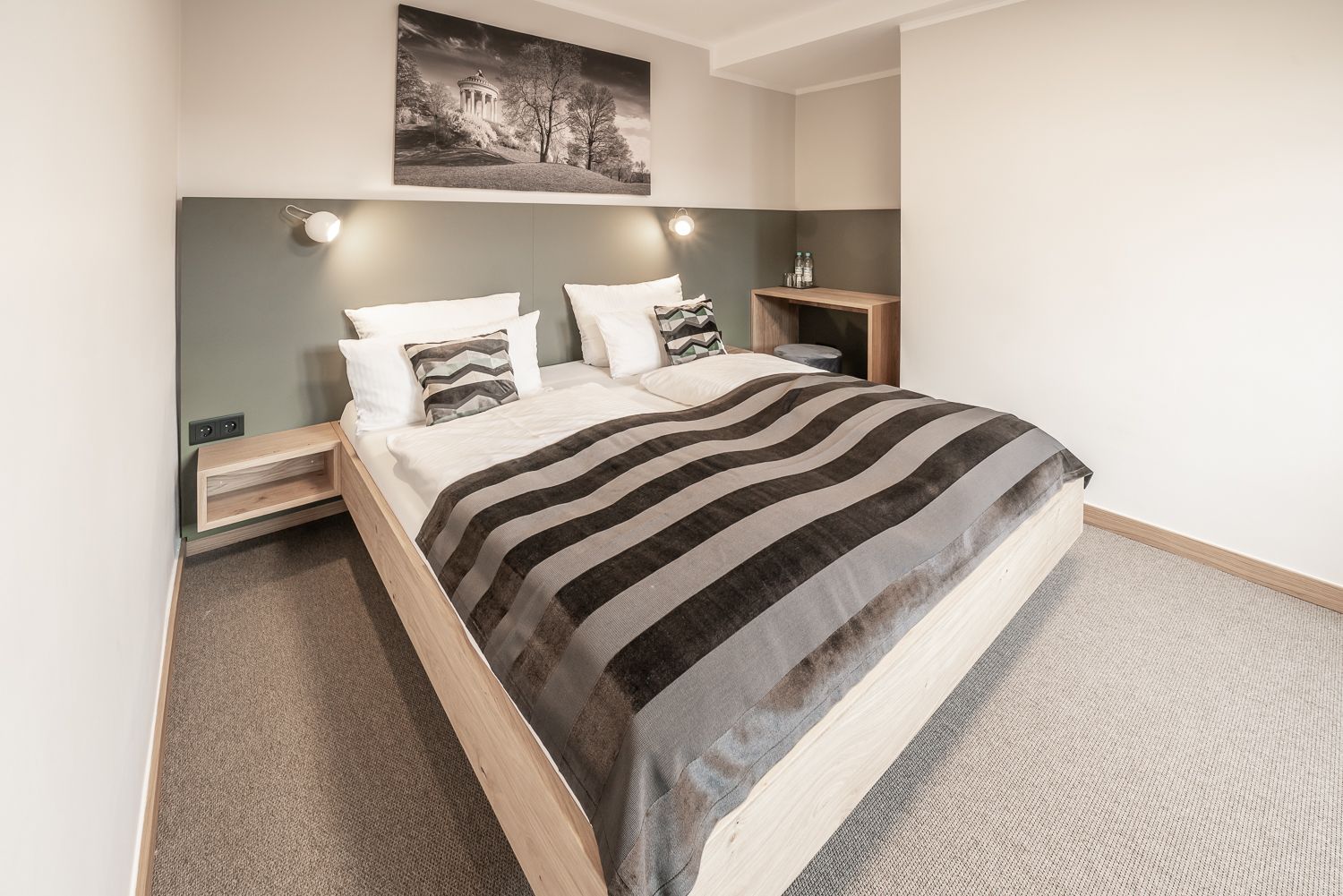 Bedroom with double bed, neutral colors, small bedside tables, and a landscape print.